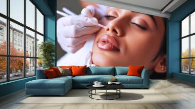 Beautician cosmetologist doing make up for Indian girl in beauty salon Wall mural