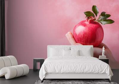 Hand holding pomegranate fruit isolated on pastel background Wall mural