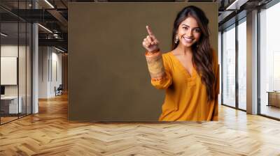 Happy indian woman pointing her finger at copy space for promotion Wall mural