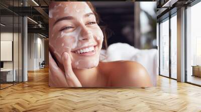 Woman smiles when applying foam for washing on her face Wall mural