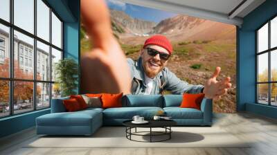 Adventure trip on Vachkazhets mountain circus, Kamchatka Russia. Tourist hipster man on volcano background make selfie photo on action camera Wall mural