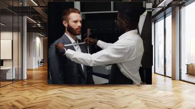 African American tailor measures tailored suit, discusses with client size in luxury designer atelier Wall mural