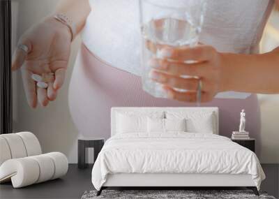 Closeup white round pill and glass of water in hand of young pregnant woman, daily vitamins for hair, skin and health of baby Wall mural