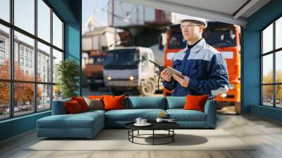 Concept banner automated logistics online internet. Dump truck driver man in uniform with tablet computer controls loading of cement to mixer on factory Wall mural