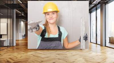 Happy builder woman construction worker with trowel plastering gray wall Wall mural