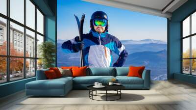 Happy skier man holding pair of skis background snowy mountains, concept sport active winter banner Wall mural