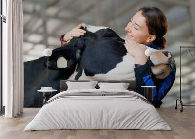 Happy young woman farm worker hugging cow as sign of concern for animal health care. Concept agriculture cattle livestock farming industry Wall mural