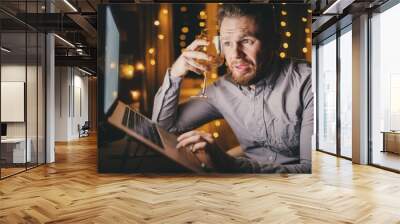 Loneliness man drinks white wine and working laptop on home workplace, stress concept Wall mural