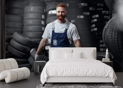 Mechanic bears to buyer two new tire on background warehouse store of tyres Wall mural