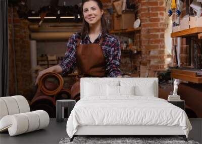 Portrait of happy young woman leather craftsman on background atelier workshop. Concept small business DIY handmade Wall mural