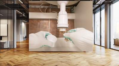 Professional male plumber eliminates blockage in siphon of sink drain pipe Wall mural