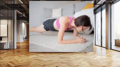 Woman training home, performs exercises on abdominal plank muscles Wall mural