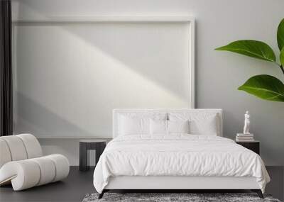 A blank picture frame on a wall next to a green plant, casting soft shadows in natural light, perfect for home decor themes. Wall mural