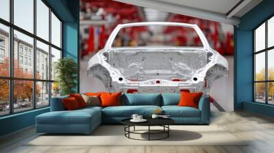 Car chassis in a modern automotive factory setting with red industrial equipment. Wall mural