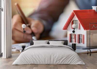 Real estate agent signing contract with miniature house on table Wall mural