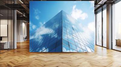 Reflective glass facade of a skyscraper against a blue sky with clouds. Wall mural