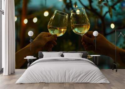 two people toasting with white wine glasses at an evening celebration. Wall mural