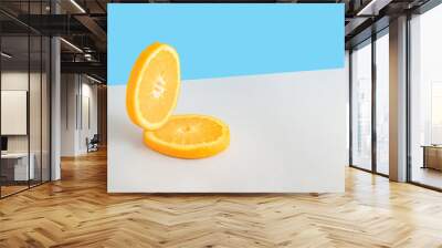 Creative summer composition with two slices of fresh orange on a blue and gray background. Minimal fresh nature or food concept. Wall mural