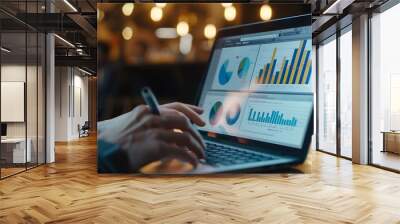 A person analyzing data on their laptop, with the screen showing graphs and tables of traffic analytics. close up.  Wall mural