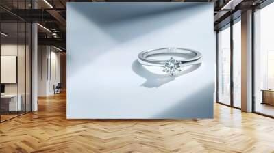 A white gold ring, specifically a silver ring with a diamond, is showcased on a white background with shadows, presenting a still life and creative photograph Wall mural