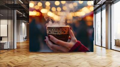 Mulled Wine at Christmas Market - Close-up of hands holding a cup of steaming mulled wine, with a blurred background of a lively Christmas market Wall mural