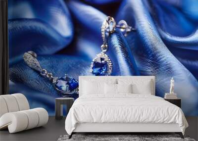 Pair of platinum earring with sapphire on blue satin background. Luxury female jewelry, close-up  Wall mural