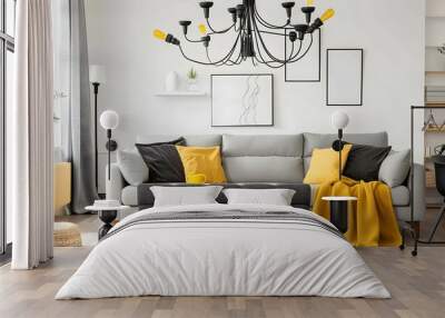 Scandinavian sofa with pillows and dark yellow blanket in bright living room interior with black chandelier Wall mural