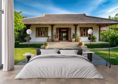 The front yard and entrance to an off-white bungalow with wooden accents in Thailand. The roof is covered by blue sky. There is one big window on each side of the two doors Wall mural