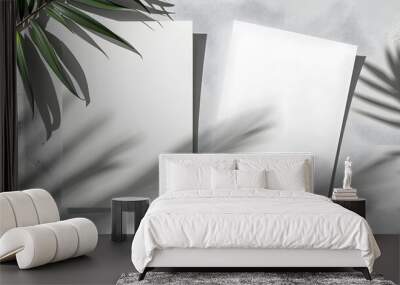 two vertical sheets of textured white paper on soft gray table background. Mockup overlay with the plant shadows. Natural light casts shadows from an exotic plant. Wall mural