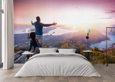 Happy couple watching the sunset in the mountains Wall mural