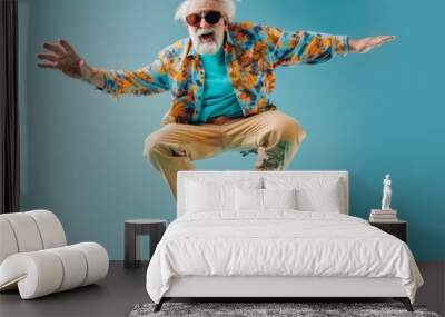 Photography of Acrobatic cute happy and smiling grandpa with sunglasses jumping with the bike against blue background Wall mural