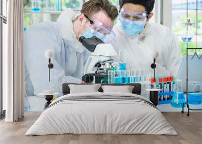 Couple male scientist wearing protection suit working with Microscope and many lab equipment for research Coronavirus  vaccine at laboratory. Wall mural