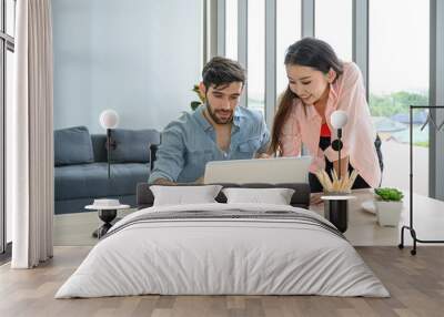 Happy and relax  lifestyle of young couple lover wearing casual dress together working on laptop notebook computer in living room at home. Wall mural