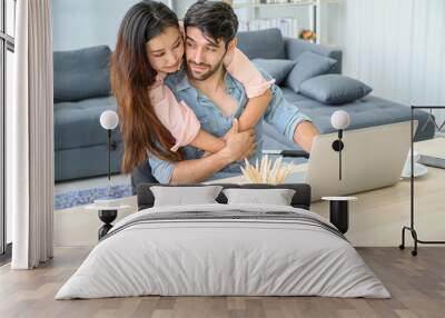 Happy and relax  lifestyle of young couple lover wearing casual dress together working on laptop notebook computer in living room at home. Wall mural