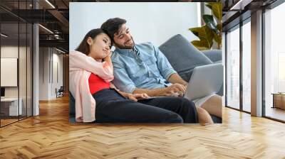 Happy and relax  lifestyle of young couple lover wearing casual dress together working on sofa with  laptop notebook computer in living room at home. Wall mural