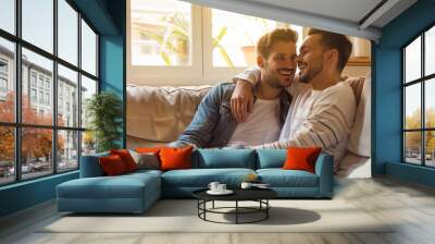 Close up young happy couple two gay men wear casual clothes together hug kiss shoulder sit on sofa couch at home flat rest spend free spare time in living room. Pride day june month love lgbtq concept Wall mural