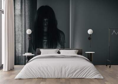 Female ghost in white dress in room. A young scary girl in an old white dress staring in to the camera with dark background. Asian woman make up ghost face at house. Scary horror concept. Wall mural