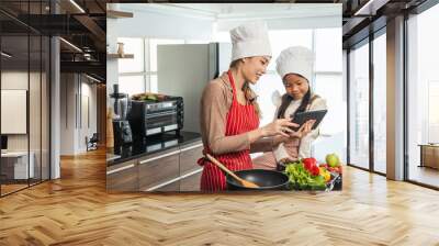 Happy moment asian mother and daughter cooking breakfast salad in the kitchen. Mom and daughter asian family having fun preparing healthy food vegetable. Positive parent and kid nice relationship Wall mural