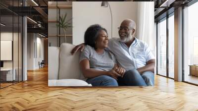 Happy adult couple sitting together on sofa in living room at home. Relaxiation, lifestyle concept Wall mural