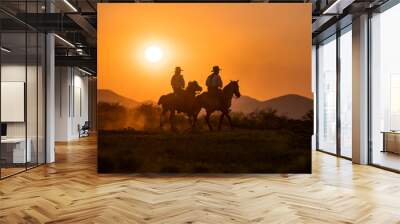 silhouette two cowboys ride with they horses under sunset Wall mural