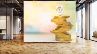 Miniature alarm clock with stack of coin under gold sun light.Saving money.Financial report.Time is money and wealth.Passive income concept. Wall mural