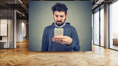 Angry annoyed man using smartphone Wall mural