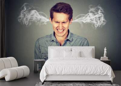 Angry man reading a text message on smartphone blowing steam coming out of ears Wall mural