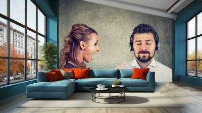 Angry woman yelling at a calm husband listening to music Wall mural