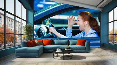 Angry young female driver, frustrated screaming while driving  Wall mural