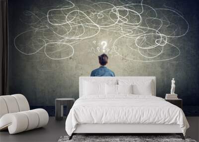 businessman sitting on chair looking at a scribble on a wall feeling confused Wall mural