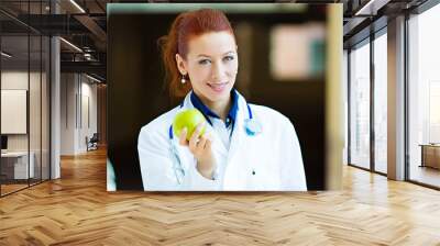 Doctor offering green apple standing in hospital hallway  Wall mural