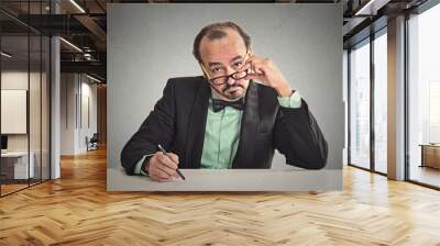 man with glasses skeptically looking at you sitting at desk Wall mural