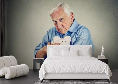 Senior man holding piggy bank on gray wall background  Wall mural