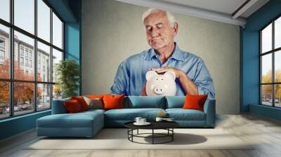 Senior man holding piggy bank on gray wall background  Wall mural